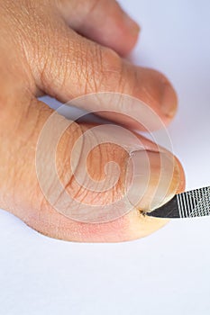 Female cleaning dirt from under toenails by nail file, Hygiene woman foot, On white background, Close up & Macro shot