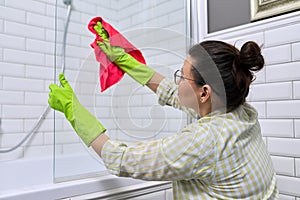 Female cleaning polishing shower glass with a washcloth with microfiber