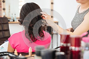 Female client with dark hair and hairdresser making hairdo