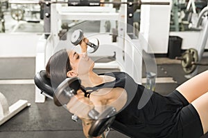 Female Client Doing Dumbbell Fly On Bench In Gym