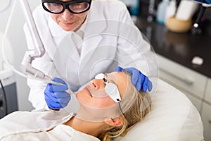 Female client receiving laser resurfacing at cosmetology clinic