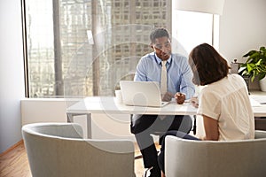 Female Client Signing Document In Meeting With Male Financial Advisor In Office