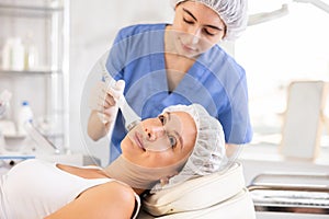 Female client undergoing anti-aging ultrasonic phonophoresis procedure on face