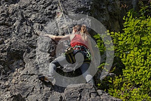 Female climber ascending the rock wall on a sunny day