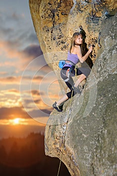 Female climber climbing with rope on a rocky wall