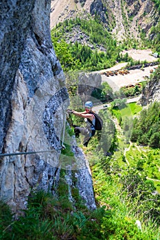 Female climber hanging from a via ferrata cable on Astragalus route, a popular tourist attraction in Bicaz Gorge/Cheile Bicazului