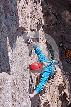 Female climber with red helmet climbing a limestone route.