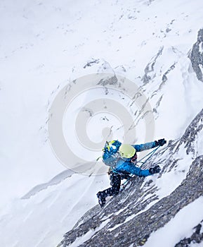 Female climber in the storm during an extreme winter climb.