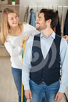 female clothes designer measuring client