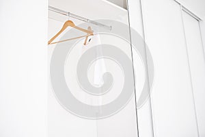 Female clothes and empty hangers on clothing rack.Sale in the store. Emptiness.Modern wardrobe with one white T-shirt and empty