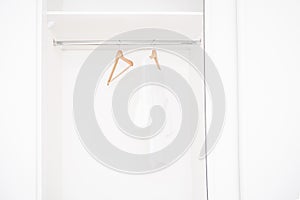 Female clothes and empty hangers on clothing rack.Sale in the store. Emptiness.Modern wardrobe with one white T-shirt and empty