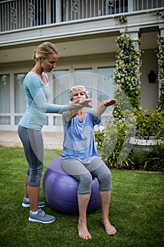 Female coach assisting senior woman in performing exercise