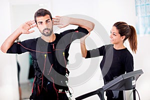 Female coach giving man ems electro muscular stimulation exerci