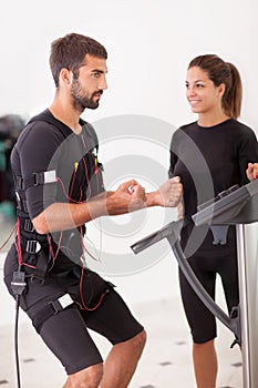 Female coach giving man ems electro muscular stimulation exercise