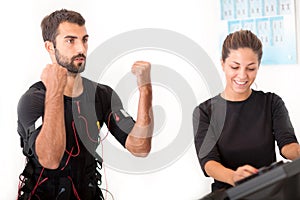 Female coach giving man ems electro muscular stimulation exercise