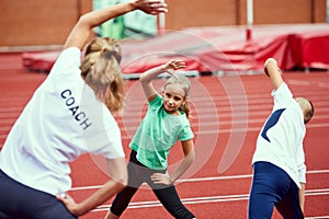 Female coach training athletes. Group of children running on treadmill at the stadium. Concept of sport, achievements