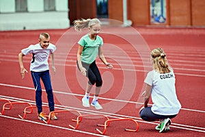 Female coach training athletes. Group of children running on treadmill at the stadium. Concept of sport, achievements