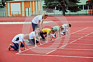 Female coach training athletes. Group of children running on treadmill at the stadium. Concept of sport, achievements