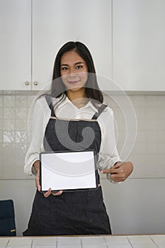 Female coffee shop owner showing digital tablet with empty screen.