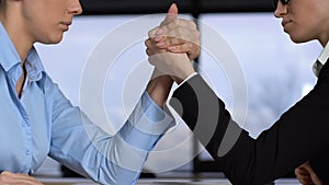 Female colleagues arm wrestling on table, career competition, business conflict