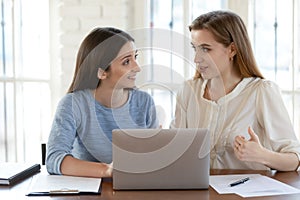 Female colleagues brainstorm work on laptop together