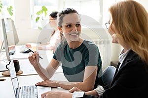 Female colleagues brainstorm working at laptop together