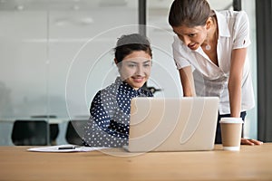 Female colleagues discuss project brainstorming using laptop