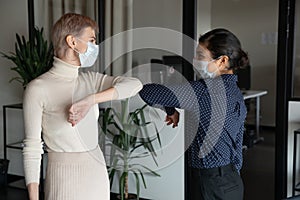 Female colleagues greeting in office touching elbows