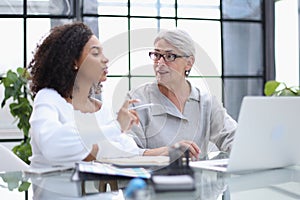 Female colleagues met in the office hall discussing work issues