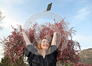 Female college graduate throwing cap into air