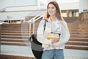 Female college student with books outdoors. Smiling school girl with books standing at campus. I'm prepared for exam