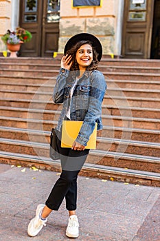 Female college student with books outdoors in the street. Smiling school girl with books standing at campus. Portrait of perfect