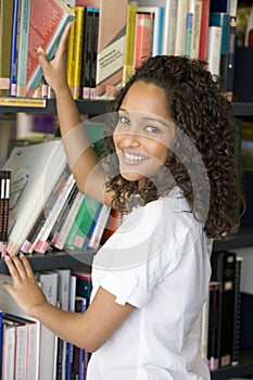 Female college student reaching for a library book