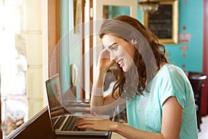 Female college student using laptop at cafe