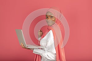 Female college student working on laptop. The beautiful young African Muslim woman is standing with smiling face