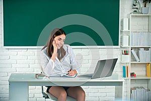 Female college student working on a laptop in classroom, preparing for an exam. Female freelancer or a student with