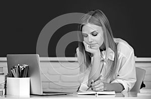 Female college student working on a laptop in classroom, preparing for an exam. Student education concept. Female