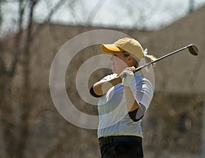 Female collegiate golfer swinging golf club