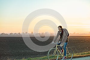 Female commuter riding a bike out of town in rural area. Young w