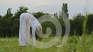 Female concentrated on limbering up before meditation outdoors. Sports woman raised hands and put them down for