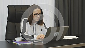 Female concentrated at work. Woman works on laptop using computer mouse in modern office. Lady boss working in her office. Busines