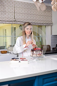 Female confectioner standing in the modern spacious kitchen, de