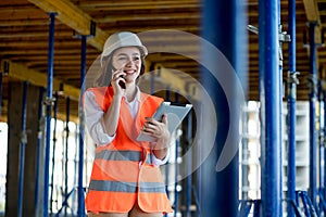 Female construction engineer. Architect with a tablet computer at a construction site. Young Woman looking, building