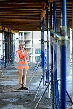 Female construction engineer. Architect with a tablet computer at a construction site. Young Woman looking, building site place on