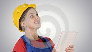 Female construction engineer with a tablet computer at a construction site on gradient background.