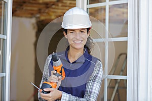 Female construction worker holding screwdriver handtool and cordless screwdriver photo