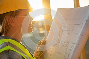 Female Construction Worker with House Plans at Construciton Site