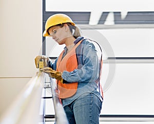 Female construction worker taking measurement