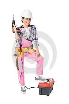 Female construction worker in uniform holding toolbox and drill