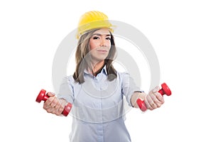 Female constructor wearing hardhat holding dumbbells photo